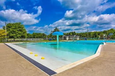 a large swimming pool with a blue umbrella in it at 1 Mi to Beach Pocono Lake Chalet with Decks in Pocono Lake