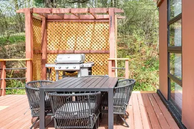 a black table and chairs on a deck with a grill at Mid Century Modern Getaway with outdoor Hot Tub in Wernersville