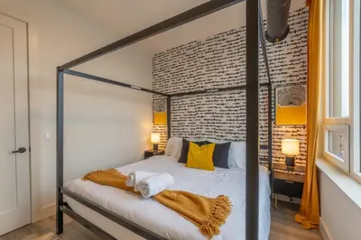 a bedroom with a canopy bed with yellow pillows at Bright and Bold Escape with NYC Views and Free Parking, Sleeps 9 and 2 Baths in Newark