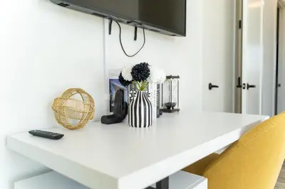 a white table with a vase of flowers on it at Bright and Bold Escape with NYC Views and Free Parking, Sleeps 9 and 2 Baths in Newark