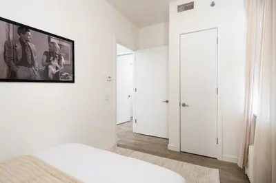 a white bedroom with a bed and a picture on the wall at Luxury 2BD nr Wall St Gym Rooftop w/d in New York