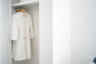 a white robe is hanging in a closet at Luxury 2BD nr Wall St Gym Rooftop w/d in New York