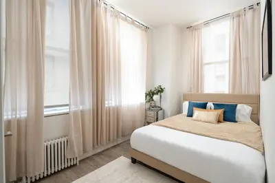 a bedroom with a large bed and a window at Luxury 2BD nr Wall St Gym Rooftop w/d in New York