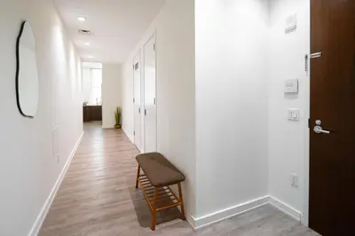 a hallway with a chair and a hallway with white walls at Luxury 2BD nr Wall St Gym Rooftop w/d in New York