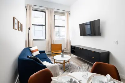 a living room with a blue couch and a tv at Spacious Luxury 2BD Downtown Gym W/D Doorman in New York