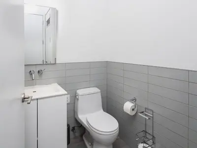 a white bathroom with a toilet and a sink at Chic 1BD with Rooftop W/D in Unit Downtown in New York