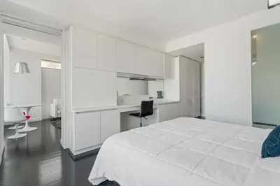 a white bedroom with a large bed and a desk at Financial District 1br w WD gym elevator NYC-1376 in New York