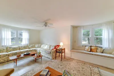 a living room with a couch and windows at Fire Pit and On-Site Pond Wooded Walton Home! in Walton
