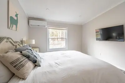 a bedroom with a large white bed and a window at EV Serene Modern Cozy Waterfront Fireplace Cottage in Livingston Manor