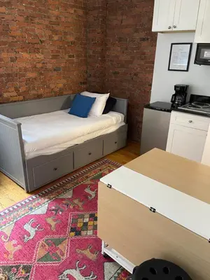 a bedroom with a bed and a brick wall at Nest 1 bedroom Aparthotel with kitchenette in New York