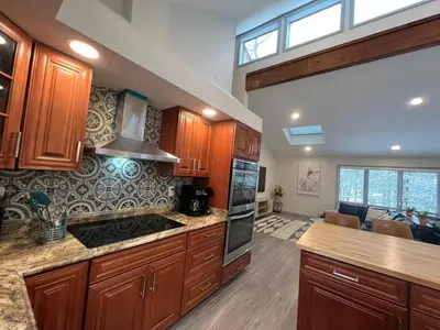 a kitchen with wooden cabinets and a stove top oven at Open Concept & Stylish-HotTub-Sauna-Billiard-Poker-BBQ in East Stroudsburg