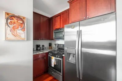 a kitchen with a stainless steel refrigerator and wooden cabinets at Grand 1BR with Rooftop Pool & Gym in Philadelphia