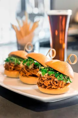 three pulled pork sandwiches on a plate with a glass of beer at Courtyard by Marriott Philadelphia Lansdale in Lansdale