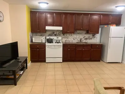 a kitchen with wooden cabinets and white appliances at The Green Place of Newark in Newark