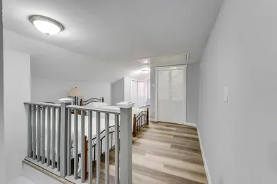 a hallway with white walls and a staircase with wood floors at Updated Minersville Townhome by ATV Trail! in Mount Pleasant