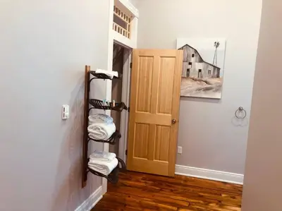 a hallway with a door and a pile of folded towels at Triple Brick on Main in Wyalusing