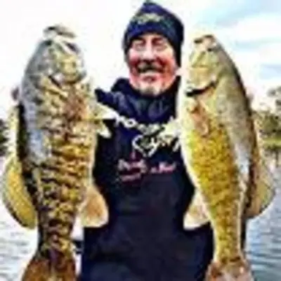 a man holding two large fish in the water at The Cast Iron Lady in Wyalusing