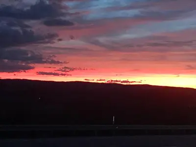 a sunset in the sky over a hill with a highway at Small Town Hideaway in Wyalusing