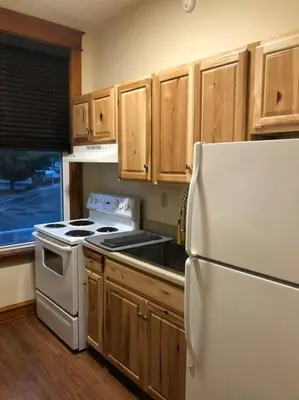 a kitchen with a white refrigerator and wooden cabinets at Small Town Hideaway in Wyalusing