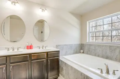 a bathroom with a tub and two sinks and a window at Spacious Ewing Township Home Home Gym and Deck!