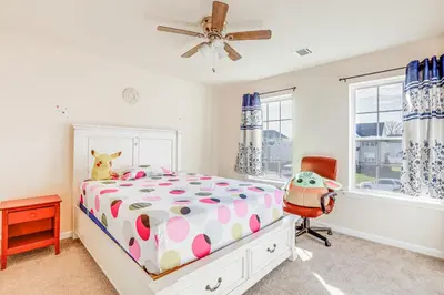 a bedroom with a bed and a chair and windows at Spacious Ewing Township Home Home Gym and Deck!