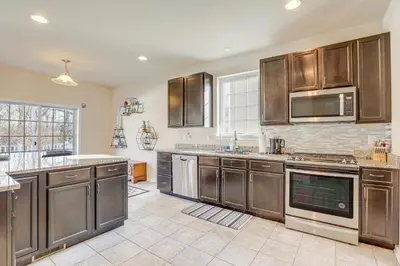 a large kitchen with wooden cabinets and stainless steel appliances at Spacious Ewing Township Home Home Gym and Deck!