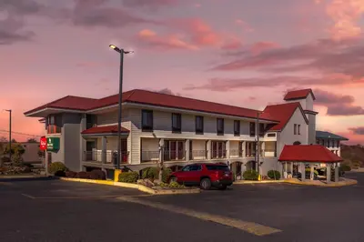 a building with a red car parked in a parking lot at HomeTowne Studios by Red Roof Lancaster in Lancaster