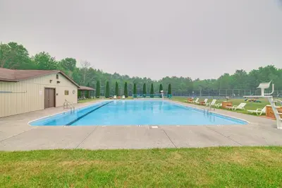 a large swimming pool with chairs and a building at Cozy Lake Wallenpaupack Cabin with Community Perks in Lake Ariel