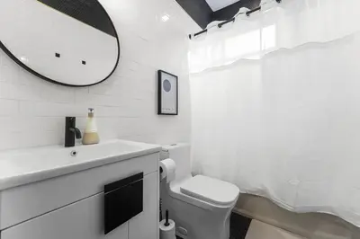 a white bathroom with a sink and a mirror at Free Parking in Prime Area w King bd in Newark