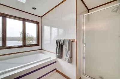 a bathroom with a tub and a window at Lake Front, Hot Tub, Fire Pit, FP, Boats, Ski in Gouldsboro