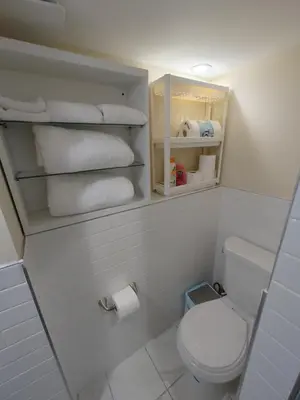 a bathroom with a white toilet and towels at Guest house in a quiet peaceful area. in Mariners Harbor