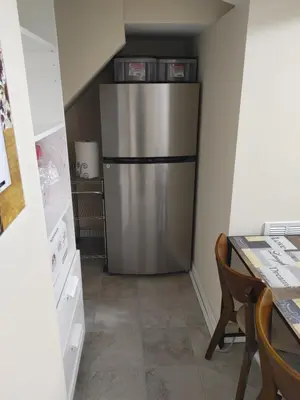 a refrigerator in a small kitchen with a table at Guest house in a quiet peaceful area. in Mariners Harbor