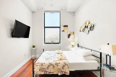 a white bedroom with a bed and a tv at XL Studio - Premier Studio with Gym Access in Philadelphia