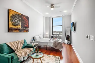a living room with a bed and a green couch at XL Studio - Modern Studio with Rooftop Pool in Philadelphia