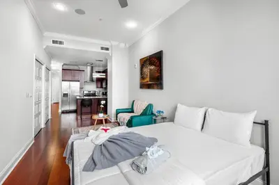 a bedroom with a white bed and a living room at XL Studio - Modern Studio with Rooftop Pool in Philadelphia