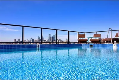 a large swimming pool with a city skyline in the background at XL Studio - Modern Studio with Rooftop Pool in Philadelphia