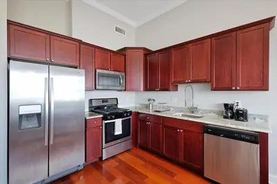 a kitchen with wooden cabinets and stainless steel appliances at XL Studio - Luxury Studio Near Center City in Philadelphia