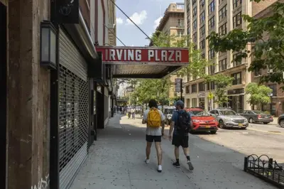 two people walking down a street under a hanging pizza sign at Chic One Bedroom Retreat in Downtown Manhattan in New York