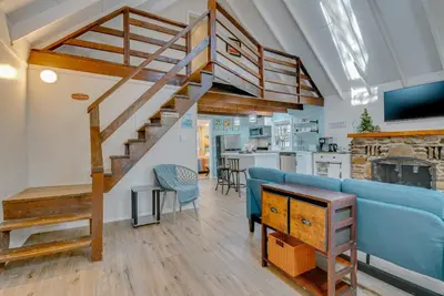 a living room with a blue couch and a staircase at Arrowhead Lake Access Cabin with Resort Amenities in Pocono Lake