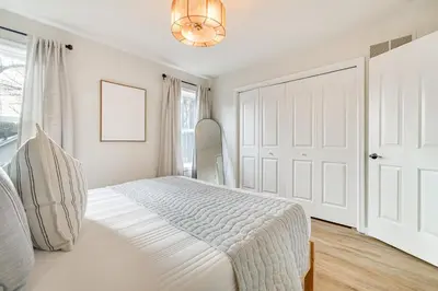 a white bedroom with a bed and a door at Beach and Lake Access Family Poconos Home with Deck in Tobyhanna