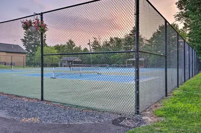 a chain link fence with two tennis courts at Beach and Lake Access Family Poconos Home with Deck in Tobyhanna