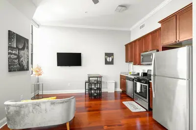 a kitchen with a stainless steel refrigerator and wooden cabinets at XL Studio - Chic Flat - Rooftop Pool & Gym in Philadelphia