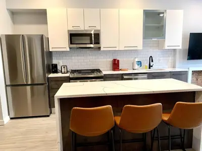 a kitchen with a stainless steel refrigerator and two bar chairs at Veau3 1BD 1BA minutes to NYC in Newark