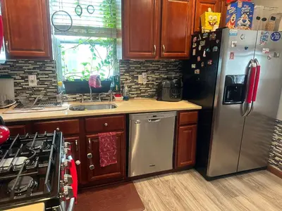 a kitchen with stainless steel appliances and wooden cabinets at Genevieve’s comfort pad in Jersey City