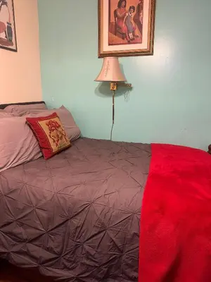a bedroom with a bed with a red blanket at Genevieve’s comfort pad in Jersey City