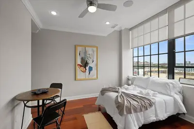 a bedroom with a bed and a table and a window at XL Studio - Magnificent Studio with Rooftop Pool in Philadelphia