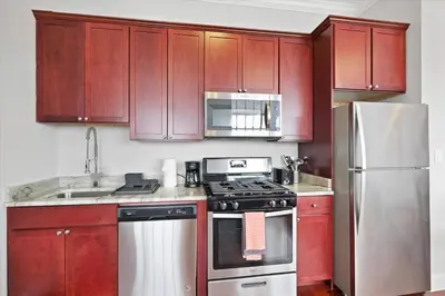 a kitchen with red cabinets and a stove and refrigerator at XL Studio - Magnificent Studio with Rooftop Pool in Philadelphia