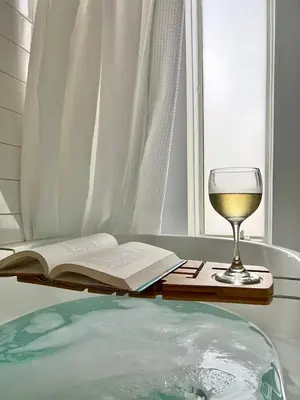 a bath tub with a book and a glass of wine at Modern chalet for 8 people with Fireplace, Hot Tub and nearby Skiing in Tobyhanna