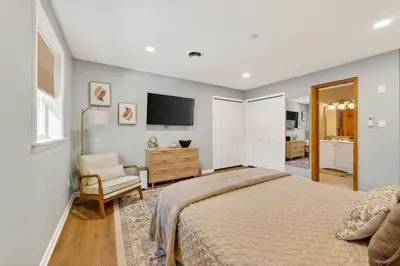 a bedroom with a bed and a chair and a tv at The Edamame House in Nazareth