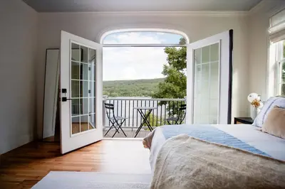 a bedroom with a bed and an open door to a balcony at Lakeview Villa with Private Hot Tub, Firepit & Spacious Decks with Breathtaking Cliff Views in Greenwood Lake